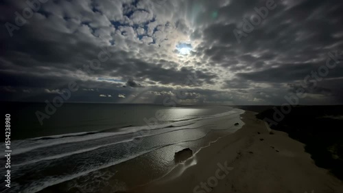 Ocean Waves Crashing on Sandy Beach Under Dramatic Cloudy Sky