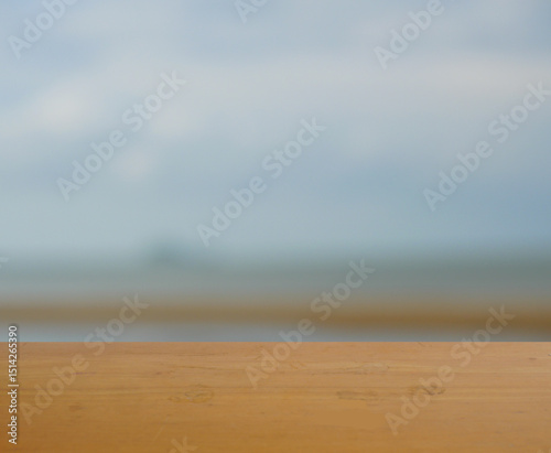 Fototapeta Naklejka Na Ścianę i Meble -  Empty brown wooden table surface for product placement with blur blue sea with sky with white cloud and brown beach in background