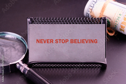 NEVER STOP BELIEVING motivational phrase close-up on a gray business card