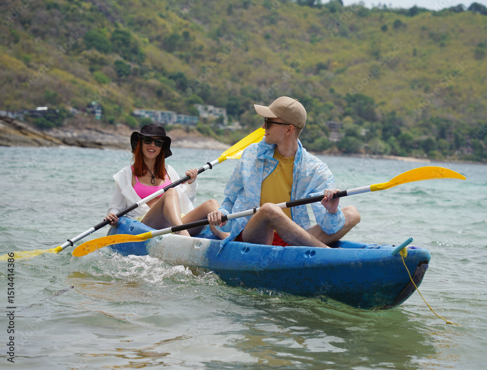 Naklejka premium The young couple are happily navigating together in a light blue kayak with yellow paddles