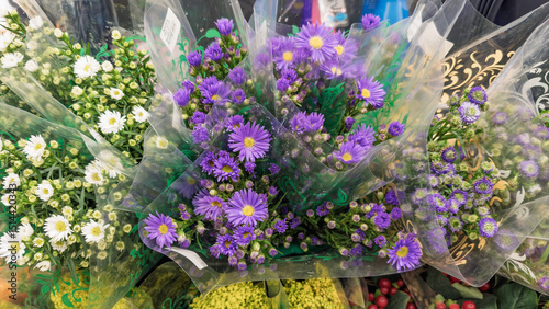 Bouquets of fresh flowers wrapped in transparent plastic with purple and white asters, ideal for florists, weddings, and romantic gifts.
