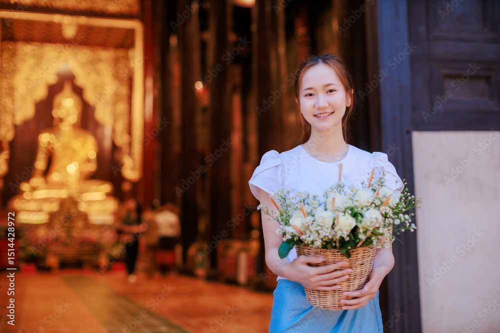 Fototapeta premium beautiful Thai woman holding flower basket worship Chiang Mai City Pillar Inthakin Festival, crowd buddhist people make merit with flowers in Wat Chedi Luang temple at night