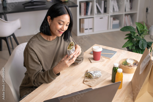 Asian woman eating healthy meal while working, Businesswoman having a lunch break at the office