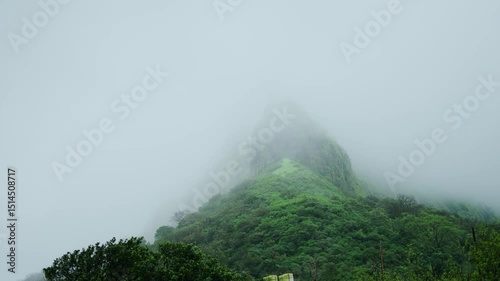 4K shot of clouds covering the Lohgad fort during the monsoon season near Lonavala in Maharashtra, India. Fog covers the fort on a cliff due to the moving clouds and rain in Monsoon season.