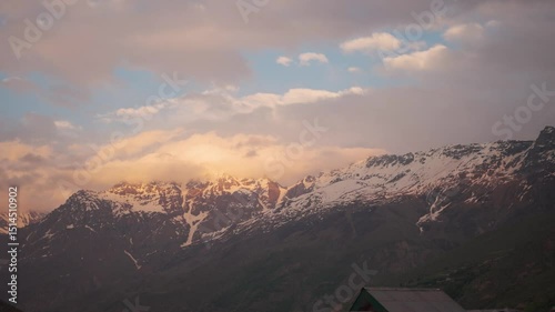 4K shot of orange clouds above the snowy Himalayan mountain peaks during the sunset as seen from Keylong in Lahaul, Himachal Pradesh, India. Scenic sunset in the Himalayas background with copy space.