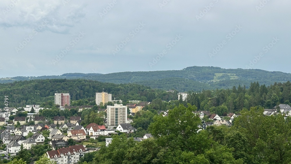 Obraz premium Panoramic view of the charming town of Herborn, Germany, captured from the top of the Aussichtsturm Dillblick observation tower. The image reveals a picturesque blend of historic rooftops, green hills