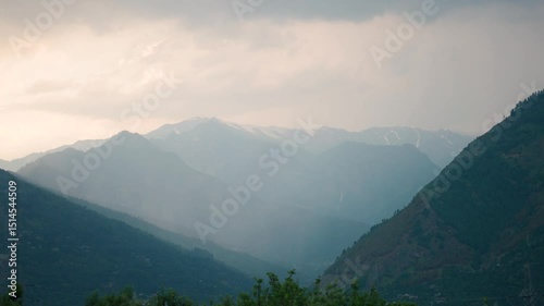 4K shot of Sun rays above the Himalayan mountains during sunset after rainfall during the monsoon season as seen from Naggar near Manali in Himachal Pradesh, India. God rays above the mountain peaks.