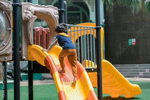 Happy child sliding down a colorful playground slide on a sunny day. Outdoor fun, childhood joy, and active play in a safe, urban recreational space.