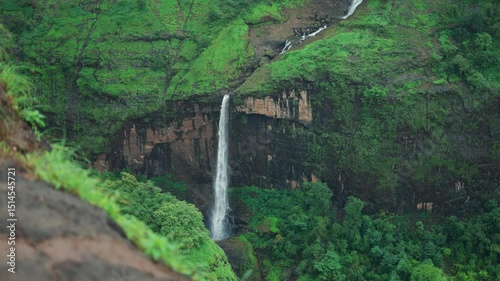 4K Slow motion shot of ring waterfall falling from a mountain cliff as seen from Savlya Ghat view point in Tamhini Ghat near Pune in Maharashtra, India during the monsoon season. Scenic waterfall view