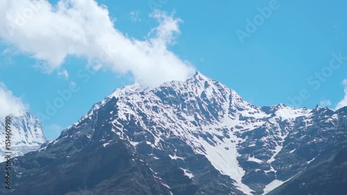 Landscape shot of snowy Himalayan mountain peaks with clouds above them as seen during a cloudy day in summer season at Tandi village in Lahaul and Spiti district, Himachal Pradesh, India.