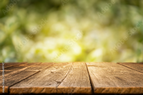 Slika na platnu Rustic wooden tabletop with a blurred green forest background, ideal for display