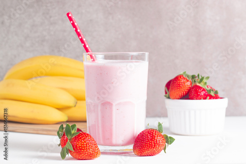 Glass of fresh strawberry milkshake, smoothie and fresh strawberries on white and wooden background. Healthy food and drink concept.
