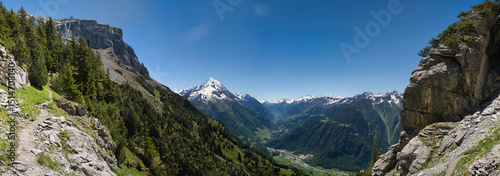 Large panorama in the Swiss mountains with hiking trail and mountain Bristen under blue sky