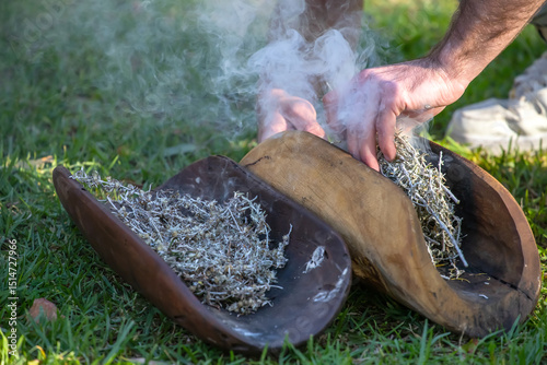 Australian Aboriginal smoking ceremony, human hands and wooden dish with a smoke of burning tree branches, the ritual rite at the community event, symbol of joining to the indigenous culture