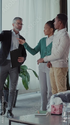 House on sale. Caucasian bearded adult rela estate agent showing new modern apartment home for african american young married couple.