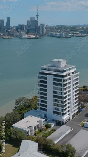 Aerial view of Auckland, New Zealand, showcasing a modern apartment building overlooking the harbor and city skyline. Sunny day, calm waters. Bayswater, Auckland, New Zealand photo