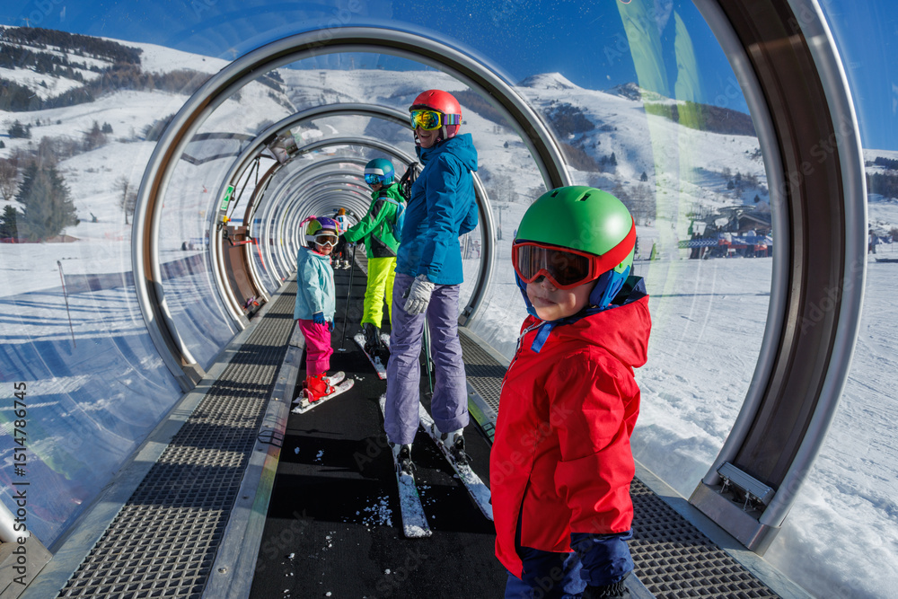 Obraz premium Happy family enjoying skiing in snowy tunnel lift on a sunny day