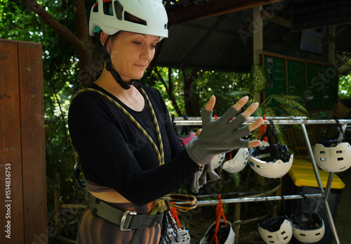 A man is assisting a woman for safety purposes before engaging ride on a zip line