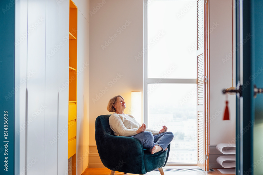 An elderly woman is sitting in an armchair in the lotus position An elderly woman is sitting in an armchair in the lotus position