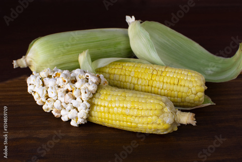 two corns with corn grains and popcorn on a table