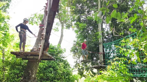 A man and a woman is walking across a challenging ropes course in the extreme park