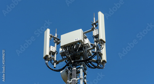 Telecommunications cell tower with multiple antennas against blue sky.
