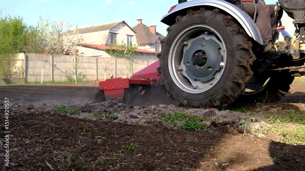 Tractor cultivating soil in the garden. Selective focus. Tractor cultivating soil in the garden. Selective focus.