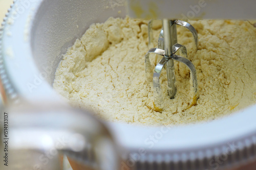 Automatic mixer blending flour with milk and eggs to create a smooth batter for baking or cooking