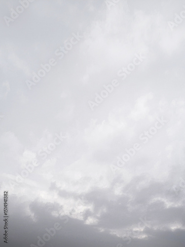 淡いやわらかな空に黒い雲が近づいてきて雨が降りそうな余白が多く文字入れしやすい風景画像。