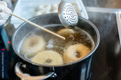 Bagels in the water being boiled before being baked  photo