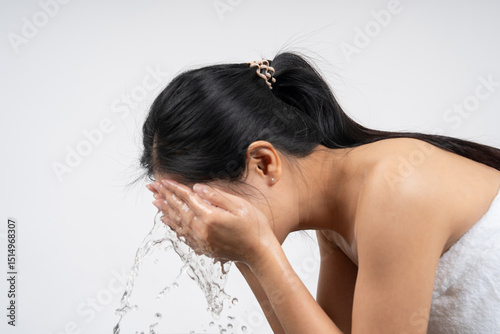 Beautiful woman wearing white towel after shower, washing face with water