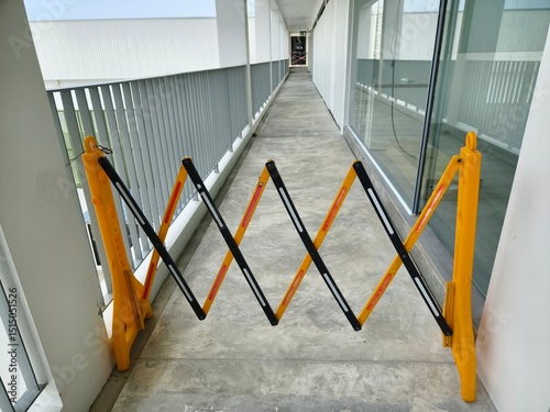 A bright yellow and dark black barrier is in the center of a hallway