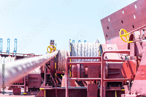 Large mooring winch on a ship's deck, featuring thick, braided ropes wound around a cylindrical metal drum. 