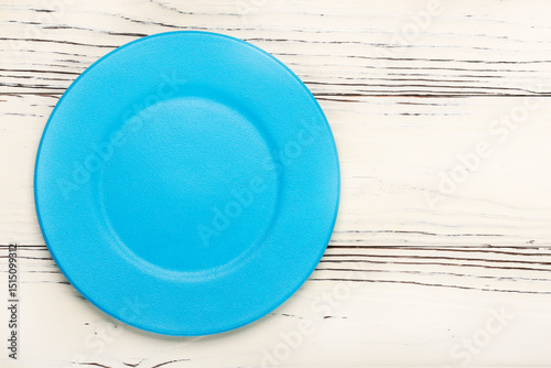round empty blue plate on white wooden background