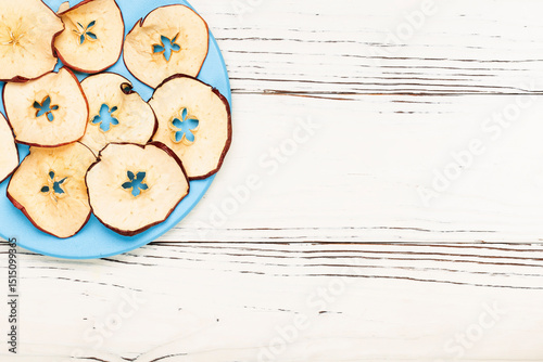 round blue plate with round apple chips on white wooden background