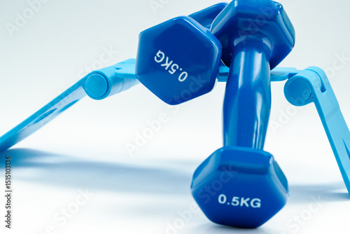 Two light blue dumbbells are placed on a light blue foldable phone or tablet stand against a white background