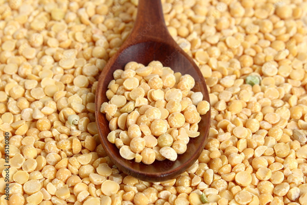 Fototapeta premium A wooden spoon with dry yellow peas lies on the surface. 
