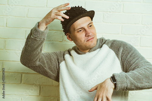 A man wearing a black cap and a gray sweater is captured in motion, dancing gracefully with fluid movements. His outfit contrasts against the background as he enjoys his dance.