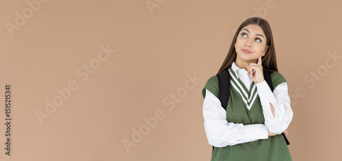 Cute woman thinking about smth. Young brunette student girl is thoughtful with backpack on brown background