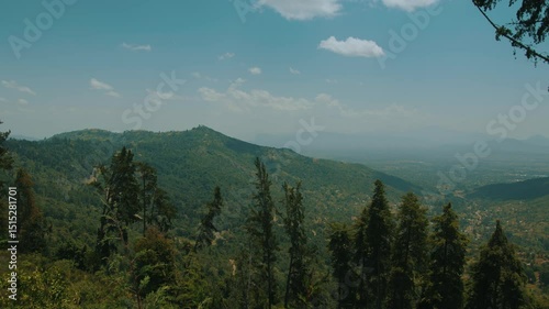 View of majestic green mountain ranges in haze around huge valley with settlements. Slow motion. Grandiose peaks and vast landscapes evoke sense of awe and delight. Travel and tourism concept