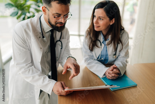 Two doctors discussing medical chart at hospital desk