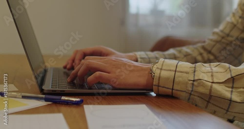 Engaging in productive laptop work while actively typing with hands on a stylish desk setup