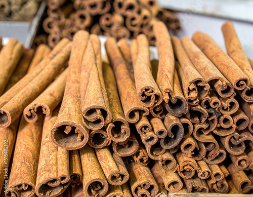 Numerous tightly rolled cinnamon sticks are stacked in large quantities inside a storage facility, showcasing their rich texture, natural color, and aromatic appeal in bulk form. photo