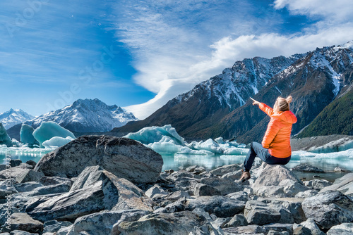 Lone tourist admiring the mountain  and glacial lake and iceberg scenery in the Tasman valley