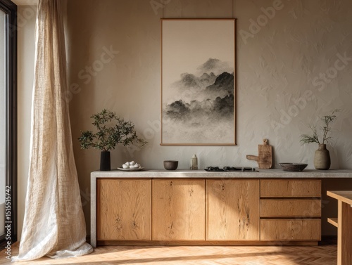 A kitchen with a wooden counter and cabinets. A framed picture of mountains hangs on the wall. A vase with flowers sits on the counter