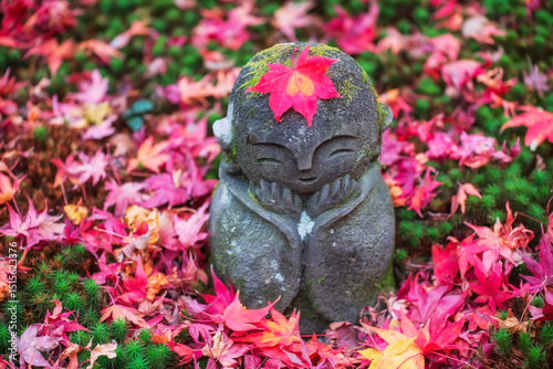 Jizo smiling Buddha with red fall maple leaf at enkoji temple, Kyoto photo