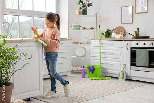 Cute girl cleaning counter in kitchen