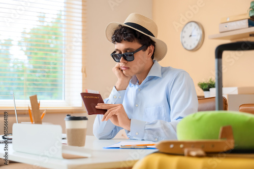 Sad businessman with passport waiting for summer vacation in office