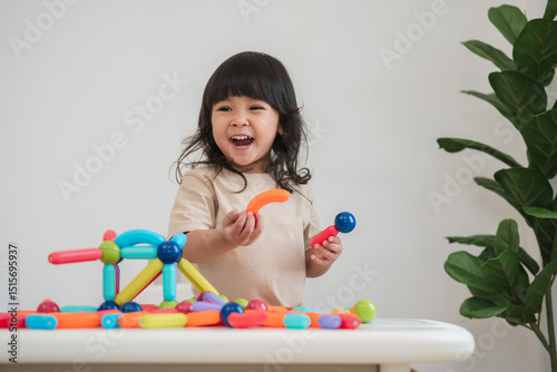 toddler girl playing colorful magnetic construction toy