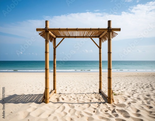 Bamboo wedding arch with thatched roof on tropical beach with turquoise ocean and blue sky